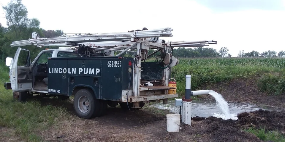 The Lincoln Pump service rig set up over a well in an eastern Missouri field, water discharging beside the truck