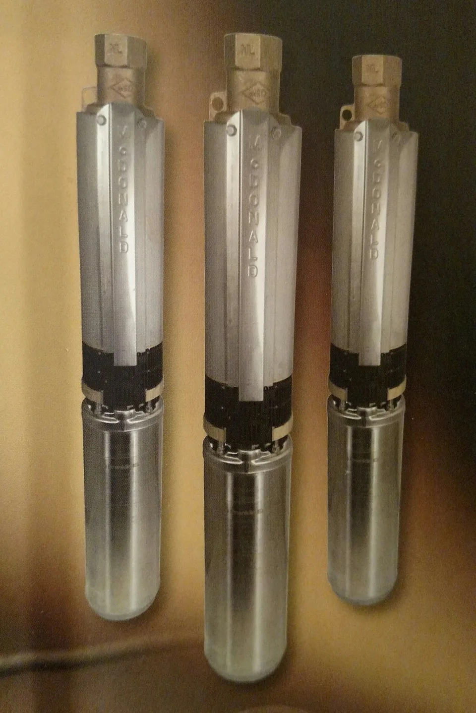 Three stainless steel submersible well pumps on the shelf at Lincoln Pump Co, ready to install