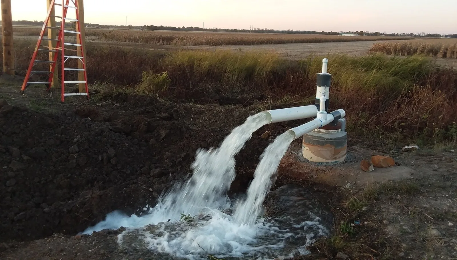 A newly drilled well flowing clear water at full rate during a flow test at sunset in eastern Missouri